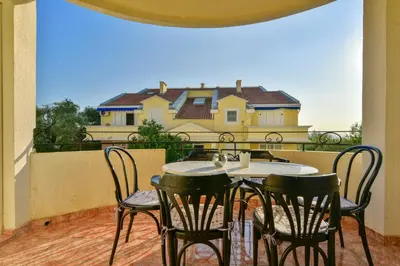 a table and chairs on a balcony with a house at Apartment Ruzica in Sveti Stefan