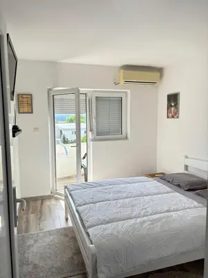 a white bedroom with a bed and a window at Saša Apartments in Sutomore