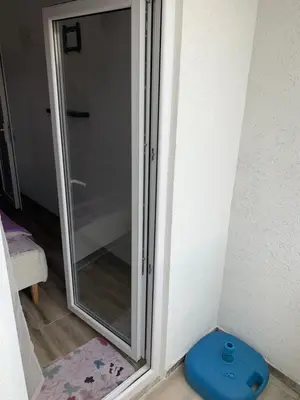 a glass shower door with a blue stool next to it at Saša Apartments in Sutomore