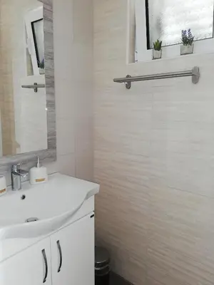 a white bathroom with a sink and a mirror at Luna apartment in Petrovac na Moru
