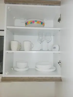 a white shelf with plates and glasses and a bowl at Luna apartment in Petrovac na Moru