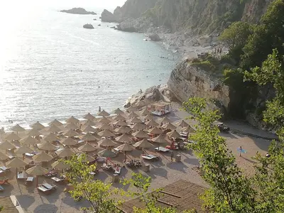 a group of umbrellas and chairs on a beach at Luna apartment in Petrovac na Moru