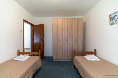 a room with two beds and a wooden cabinet at House Gorica in Bar