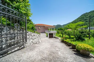 a driveway leading to a house with a stone fence at House Gorica in Bar