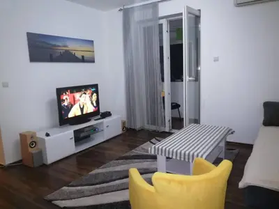 a living room with a tv and a table and chairs at Yellow apartment, central Podgorica in Podgorica