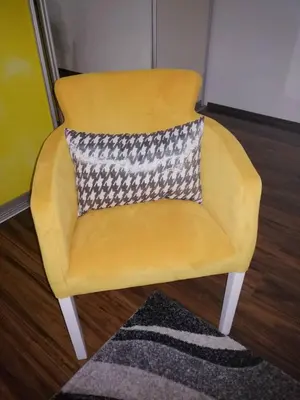 a yellow chair with a pillow on a rug at Yellow apartment, central Podgorica in Podgorica