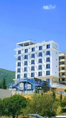 a large white building with a blue bridge in front of it at Hotel Svarog in Becici