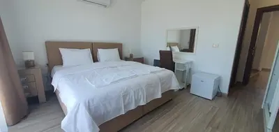 a bedroom with a large bed with white sheets and a mirror at Hotel Svarog in Becici