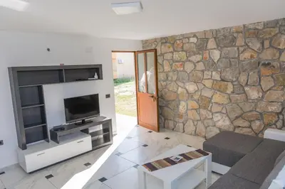 a living room with a tv and a stone wall at Leonida Resort in Donji Štoj