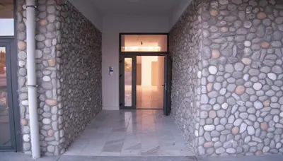 a hallway with a stone wall with a door at Stan na dan Podgorica in Podgorica
