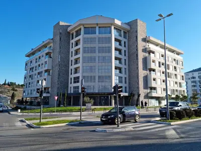 a car parked in front of a large building at Stan na dan Podgorica in Podgorica