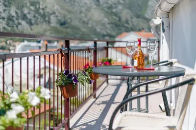 a table on a balcony with a bottle of wine at Apartments Feniks in Kotor