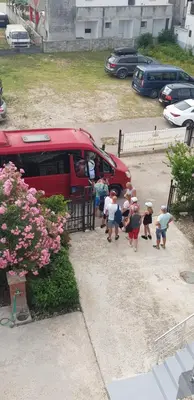 a group of people walking towards a red bus at Apartment's Meti in Ulcinj