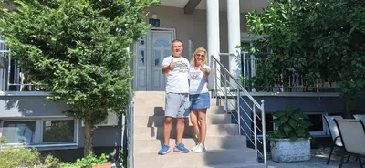 a man and woman standing on the steps of a house at Apartment's Meti in Ulcinj