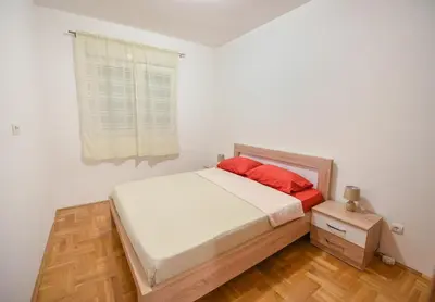 a bedroom with a bed with red pillows and a window at Enigma in Podgorica