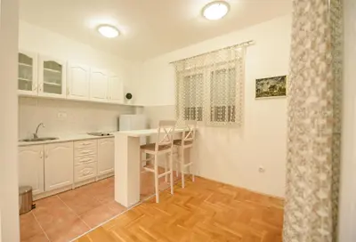 a kitchen with white cabinets and a table and chairs at Enigma in Podgorica