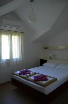 a bedroom with a bed with two purple pillows on it at Apartments TMV Dragovic in Sveti Stefan