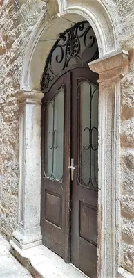 a wooden door in a stone building with an arch at Biuk in Kotor
