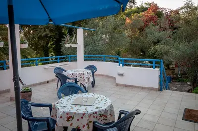 a patio with tables and chairs and an umbrella at Apartments Villa Petranović in Budva