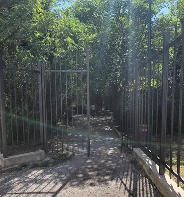 a gate in a park with trees behind it at Cicki Apartments II in Podgorica
