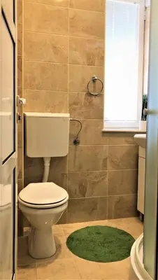 a bathroom with a toilet and a green rug at Cicki Apartments II in Podgorica