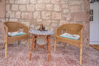 two wicker chairs and a table with a candle on it at Stone Beach Apartments in Pržno