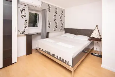 a bedroom with a bed and a window at Stone Beach Apartments in Pržno