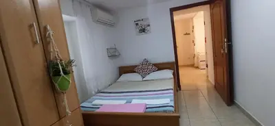 a small bedroom with a bed and a hallway at Stone Beach Apartments in Pržno