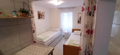 a small room with two beds and a window at Stone Beach Apartments in Pržno