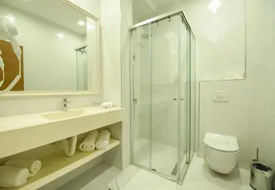 a bathroom with a shower and a sink and a toilet at Hotel Lazaro in Podgorica