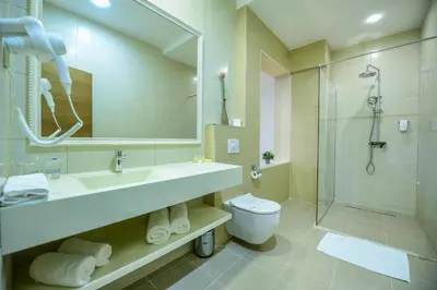 a bathroom with a sink and a shower and a toilet at Hotel Lazaro in Podgorica