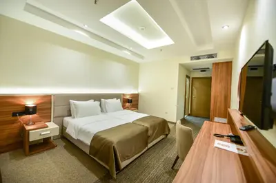 a hotel room with a bed and a flat screen tv at Hotel Lazaro in Podgorica