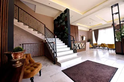 a lobby with stairs and a chair and tables at Hotel Lazaro in Podgorica