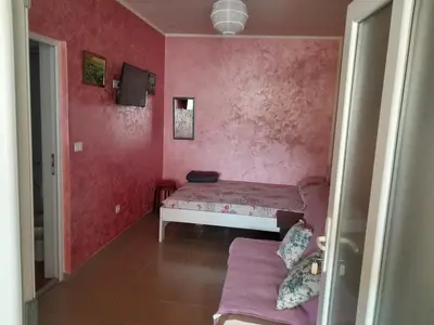 a small room with a bed and a pink wall at Apartmani Holiday Sutomore in Sutomore