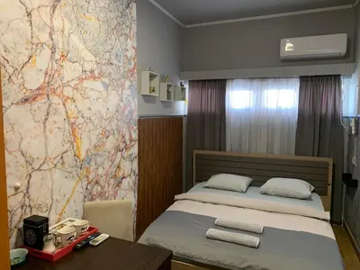 a bedroom with a bed and a table and a wall at Apartman Dacaa in Podgorica