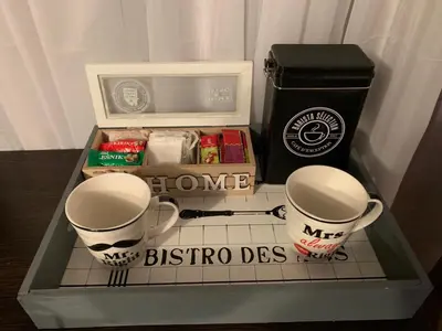 two coffee cups sitting on a shelf with a box at Apartman Dacaa in Podgorica