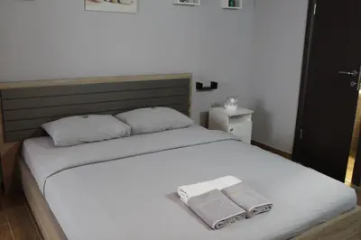 a bedroom with a white bed with two towels on it at Apartman Daca in Podgorica