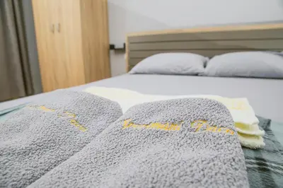 a bed with a gray blanket and two pillows at Apartman Daca in Podgorica