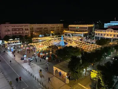 a group of people walking around a city at night at Apartman Daca in Podgorica