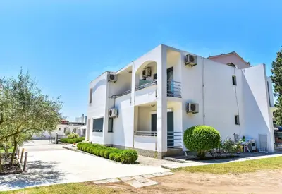 a white building with trees in front of it at Apartments Laguna in Ulcinj