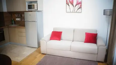 a white couch with two red pillows in a kitchen at Apartments LM RESIDENCE in Rafailovici