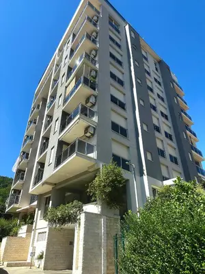 a tall apartment building with a tree in front of it at Square Inn in Budva