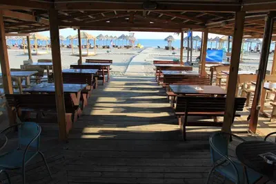 a row of tables and benches on the beach at villa elkom-appartamento giallo 1 in Ulcinj