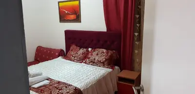 a small bedroom with a bed with a red headboard at Apartments Monte in Ulcinj