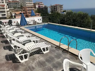 a swimming pool with white chairs next to a swimming pool at Apartments Monte in Ulcinj