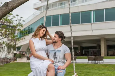 a man and a woman sitting on a swing at Hotel Sato Conference & SPA Resort in Sutomore