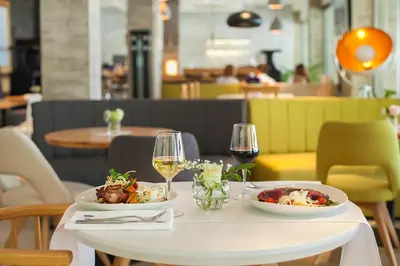 a table with two plates of food and glasses of wine at Hotel Sato Conference & SPA Resort in Sutomore