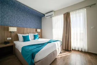 a hotel room with a large bed with blue accents at Hotel Sato Conference & SPA Resort in Sutomore