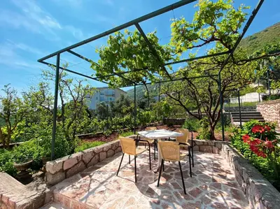 a patio with a table and chairs in a garden at Apartments Krš Medinski in Petrovac na Moru