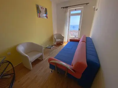 a room with a bed and a chair and a window at Apartments Krš Medinski in Petrovac na Moru